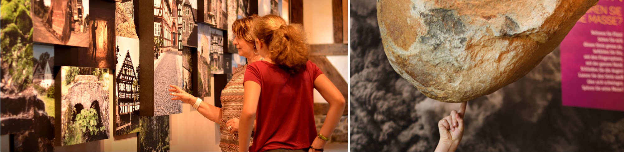 Zwei Personen betrachten eine Wandausstellung mit Architekturfotos. Rechts berührt eine Hand einen großen, hängenden Felsen.